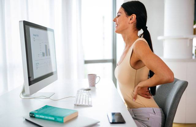 donna seduta al lavoro con mal di schiena sciatica