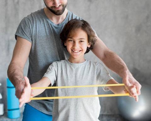 bambino fa fisioterapia con elastici
